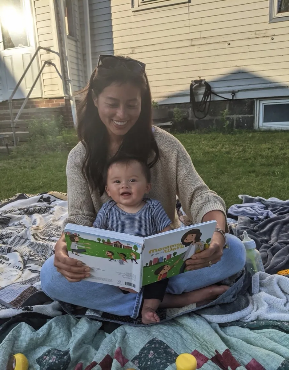A mother reading to her baby on a blanket outside