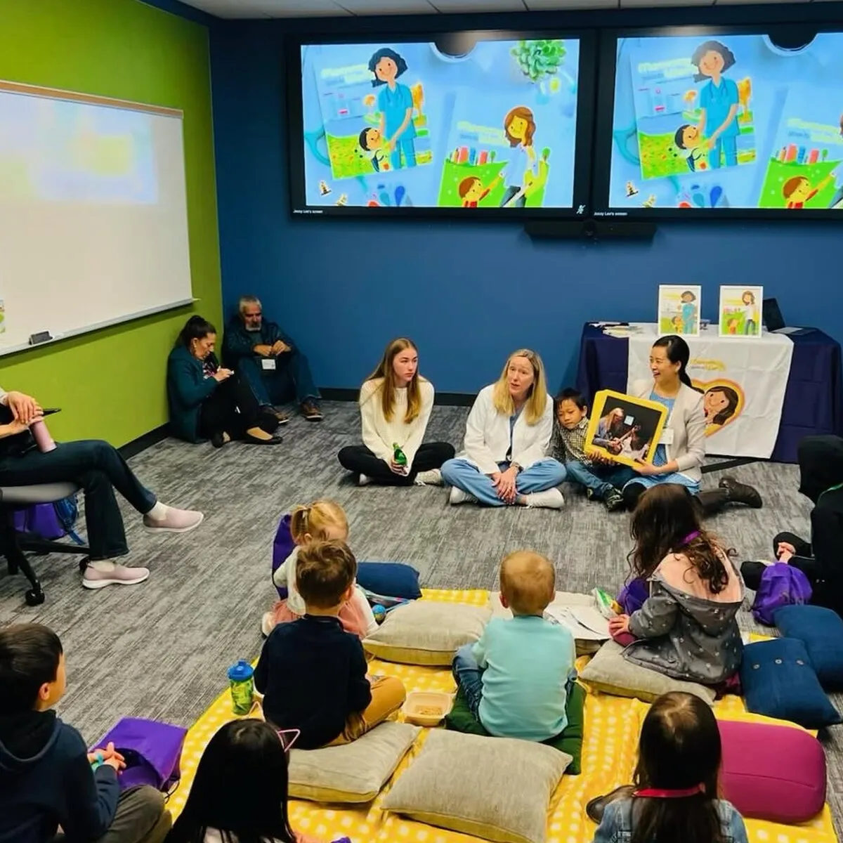 A room of children at a storytime session, the book on the screens behind